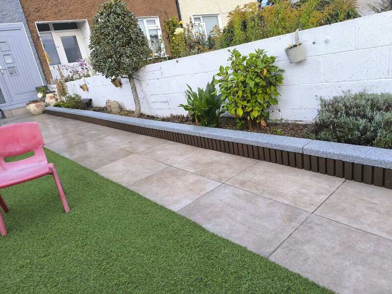 Garden at night with warm fence lighting and planting beds